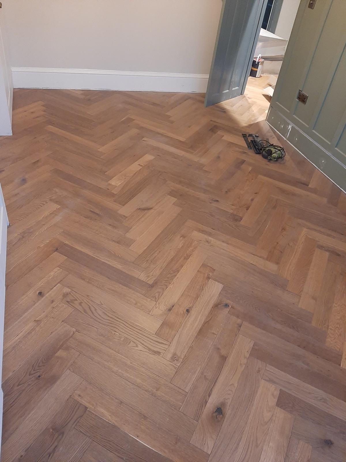Wide-angle view of herringbone flooring installation across ground floor