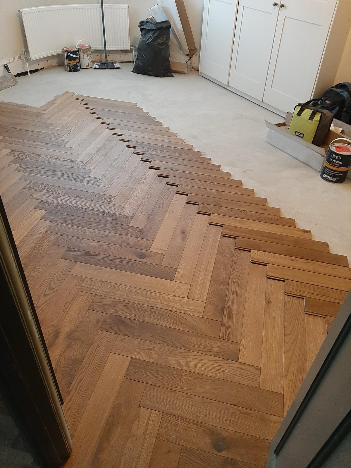 Herringbone flooring installation in progress showing subfloor preparation